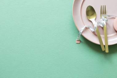 Tabak ve çatal, yeşil arka planda mezuralı kaşık. Diyet kavramı