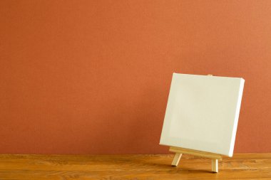 Tahta masa üzerinde boş tuval ile Easel. kahverengi arkaplan