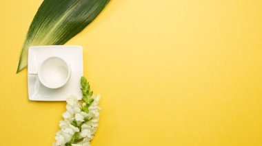 Sarı arka planda çiçekli boş kahve fincanı. düz alan, üst görünüm, kopyala boşluk