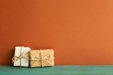 Yeşil ahşap masada beyaz ve çizgili hediye kutuları. kırmızı duvar arkaplanı