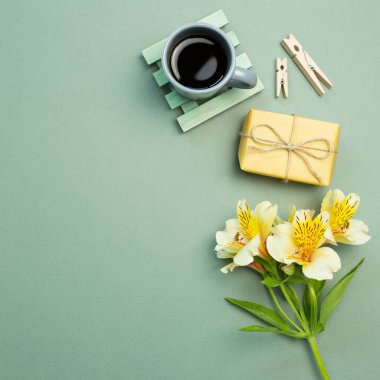 Sarı hediye kutusu, çiçek buketi, yeşil arka planda bir fincan kahve. düz alan, üst görünüm, kopyala boşluk