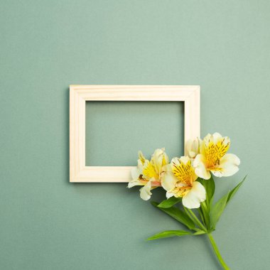 Ahşap çerçeve ve yeşil arka planda sarı çiçek buketi. Üst görünüm, boşluk kopyala