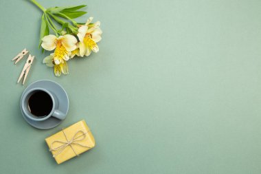 Sarı hediye kutusu, çiçek buketi, yeşil arka planda bir fincan kahve. düz alan, üst görünüm, kopyala boşluk