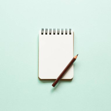 Mavi arka planda boş defter ve renkli kalem. Üst görünüm, boşluk kopyala