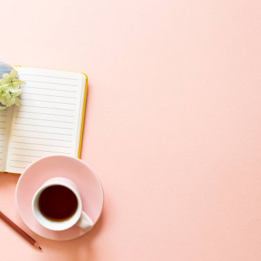 Açık defter, bir fincan çay, pembe arka planda kuru çiçekler. Günlük yaşam, çalışma alanı, öğrenim kavramı