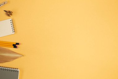 Not defteri, kalem, ataç, turuncu arka planda yapraklar. Düz konum, üst görünüm, kopyalama alanı. Çalışma ve öğrenim yeri