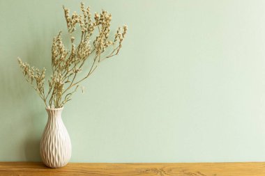 Ahşap masada kurumuş çiçek vazosu. Yeşil duvar arkaplanı. ev içi