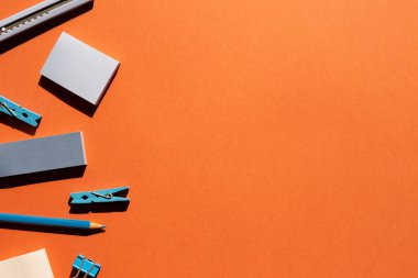 Mavi not defteri, klipsler, makas, kırmızı arka planda renkli kalem. Çalışma ve öğrenim yeri. düz alan, üst görünüm, kopyala boşluk