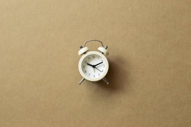 Kahverengi arka planda beyaz çalar saat. Üst görünüm, boşluk kopyala