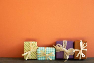 Ahşap masada renkli hediye kutuları. kırmızı duvar arkaplanı
