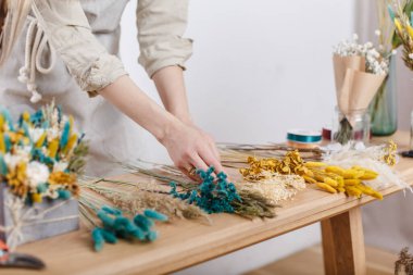 Usta çiçekçi ana derste kurutulmuş çiçek buketi yapıyor, atölyede.