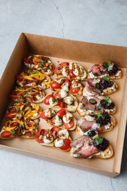 Parti ya da şenlik masası için farklı atıştırmalıklar. Domatesli Ciabatta sandviçi, jamon, krem peynir, sebze, ocak ve zeytin. Lezzetli şarap atıştırmalıkları