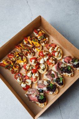 Parti ya da şenlik masası için farklı atıştırmalıklar. Domatesli Ciabatta sandviçi, jamon, krem peynir, sebze, ocak ve zeytin. Lezzetli şarap atıştırmalıkları