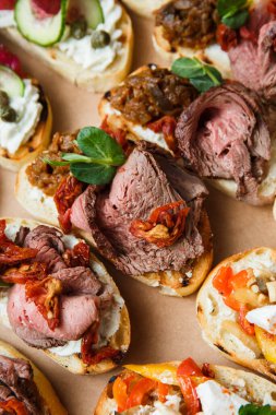 Parti ya da şenlik masası için farklı atıştırmalıklar. Domatesli Ciabatta sandviçi, jamon, krem peynir, sebze, ocak ve zeytin. Lezzetli şarap atıştırmalıkları
