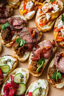Parti ya da şenlik masası için farklı atıştırmalıklar. Domatesli Ciabatta sandviçi, jamon, krem peynir, sebze, ocak ve zeytin. Lezzetli şarap atıştırmalıkları
