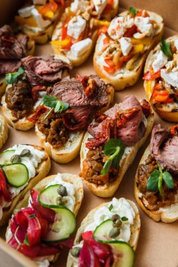 Parti ya da şenlik masası için farklı atıştırmalıklar. Domatesli Ciabatta sandviçi, jamon, krem peynir, sebze, ocak ve zeytin. Lezzetli şarap atıştırmalıkları
