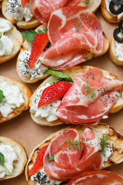 Parti ya da şenlik masası için farklı atıştırmalıklar. Domatesli Ciabatta sandviçi, jamon, krem peynir, sebze, ocak ve zeytin. Lezzetli şarap atıştırmalıkları