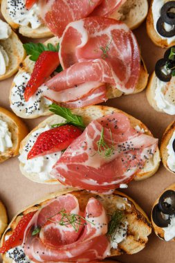 Parti ya da şenlik masası için farklı atıştırmalıklar. Domatesli Ciabatta sandviçi, jamon, krem peynir, sebze, ocak ve zeytin. Lezzetli şarap atıştırmalıkları