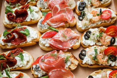 Parti ya da şenlik masası için farklı atıştırmalıklar. Domatesli Ciabatta sandviçi, jamon, krem peynir, sebze, ocak ve zeytin. Lezzetli şarap atıştırmalıkları