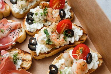 Parti ya da şenlik masası için farklı atıştırmalıklar. Domatesli Ciabatta sandviçi, jamon, krem peynir, sebze, ocak ve zeytin. Lezzetli şarap atıştırmalıkları