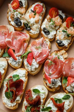 Parti ya da şenlik masası için farklı atıştırmalıklar. Domatesli Ciabatta sandviçi, jamon, krem peynir, sebze, ocak ve zeytin. Lezzetli şarap atıştırmalıkları