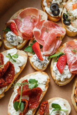 Parti ya da şenlik masası için farklı atıştırmalıklar. Domatesli Ciabatta sandviçi, jamon, krem peynir, sebze, ocak ve zeytin. Lezzetli şarap atıştırmalıkları