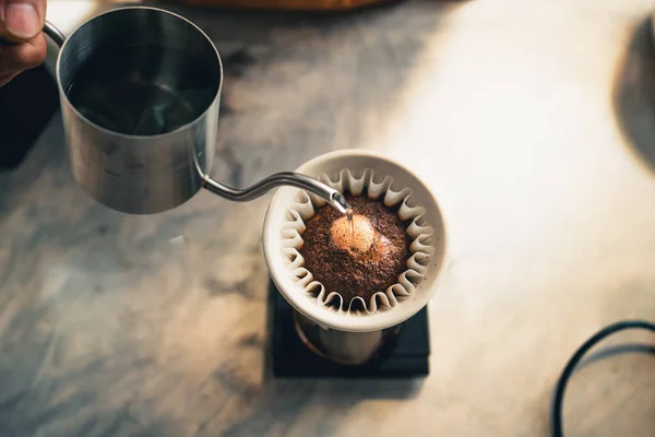 Drip coffee, barista pouring water on coffee ground with filter at home