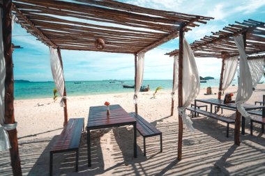 Kumsalda masalar ve sandalyeler, plajda dinlenmek plajın yanında dinlenmek için bir yer