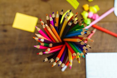 Masanın üzerine bir kutu renkli kalem, bilgisayar masası. 