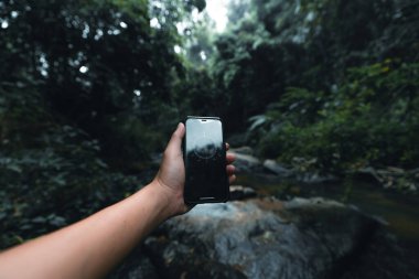 Ormanda ve pusulada el bilgisayarı, telefonda pusula. 
