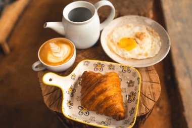 Kahvaltı, ekmek, kahve ve kızarmış yumurta tabakta.