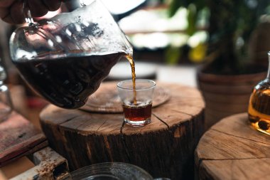 Adam cam kavanozun üstündeki kahve damlatıcısına sıcak su ekliyor..