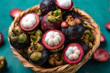 Açık mavi ahşap zemin üzerinde mangosteen meyvesi, tropikal meyve