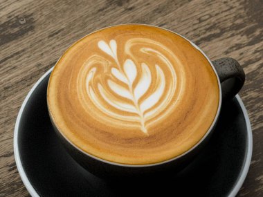 Sıcak kahve, ahşap bir masada kupada sıcak bir latte..