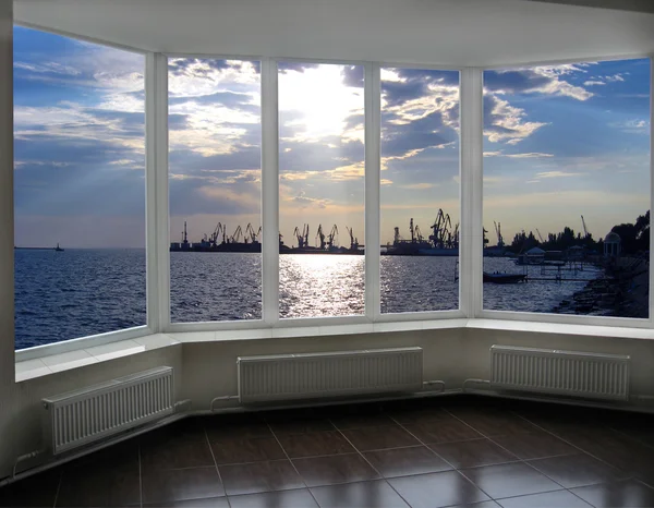 Window with view of evening sea port docks and cranes — Stock Photo, Image