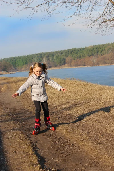 Jonge meisje gaat in rolschaatsen op de grond — Stockfoto