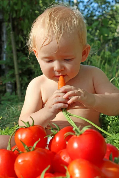 Bébé mange des carottes et des tomates mûres — Photo