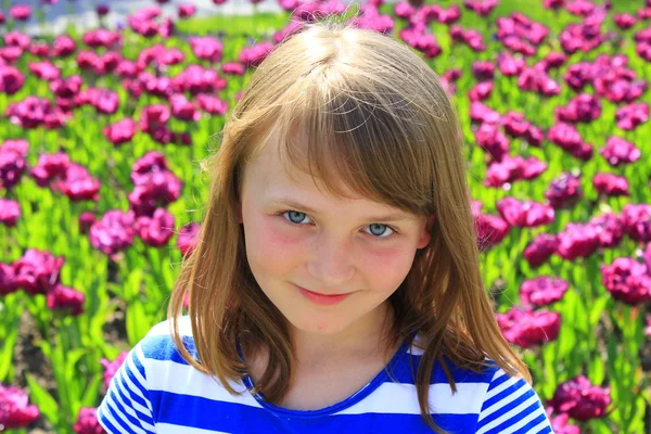 Retrato de niña parada por tulipanes lila —  Fotos de Stock