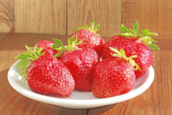 Mogna röda jordgubbar på den vita plattan på bruna — Stockfoto