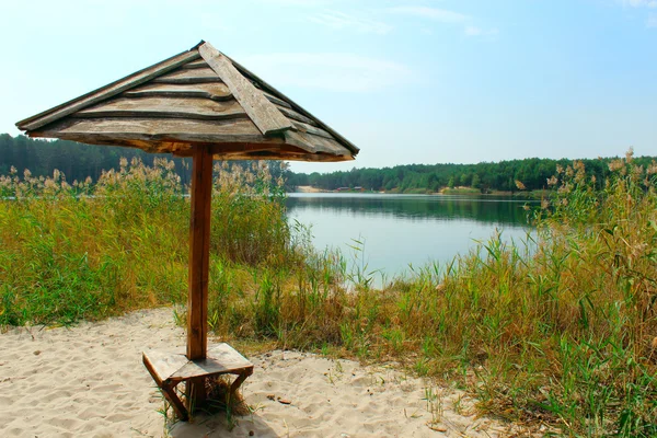 Drewniana parasol na piasku w pobliżu jeziora, w lesie — Zdjęcie stockowe