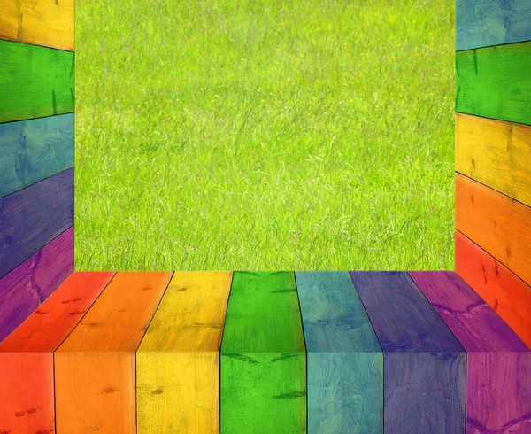 Tabel van veelkleurige houten planken en gras — Stockfoto