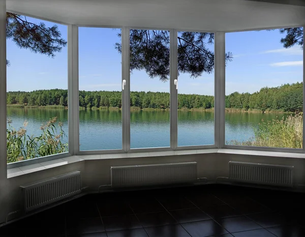 window in modern cozy room with panoramic view to forest lake. View from window to pine forest and lake. Landscape seen from room window