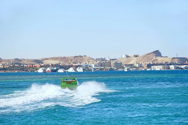 Fast boat making great splashes on sea water and rolling tourists on Red sea in Egypt. Entertainment during holidays at sea. Extreme vacation at seaside resort. People ride motorboat