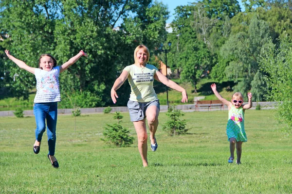 緑の芝生の上で娘たちと一緒にジャンプを楽しんでいる幸せな母親 ハッピーファミリーチーム 夏休みを楽しむ家族 家族の休日を楽しむ人々 — ストック写真