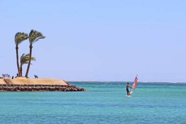 Koronavirüs karantinası sırasında Kızıl Deniz 'de sörf yapan yalnız bir adam. Yaz tatili. Yaz tatillerinde su sporu. Güzel deniz manzarası ve yalnız rüzgar sörfçüsü