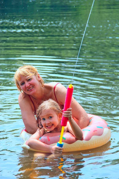 mother with daughter swim in forest lake. Family vacations at beautiful forest lake. Family enjoying time spending in summer holidays