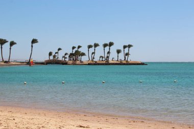Mahremiyet için güzel bir yer. Adanın üzerinde gün batımı. Deniz üzerinde şafak vakti parlak güneş. Okyanusta palmiye ağaçları ve bankları olan bir ada. Coronavirus 'tan uzakta yaz tatili