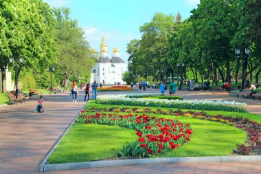 Chernihiv-Ukrayna. 17 Mayıs 2020: Şehir parkında çiçek tarhında. İnsanlar baharda lale yataklarıyla şehir parkında dinleniyor. Çiçekli süsleme. Şehirde birçok lale yetişir. Aydınlık bir günde çiçek tarhında güzel bahar laleleri