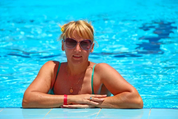 Attractive woman posing during relaxing in swimming pool during vacation. Happy girl. Young woman enjoying summer vacations. Summer holiday in tropical resort. Woman resting in swimming pool