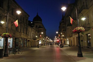 Lodz - Polonya. 18 Haziran 2019: Lodz Piotrkowska 'nın merkez caddesi. Geceleri Polonya 'nın ana turistik caddesi Lodz Piotrkowska. Piotrkowska caddesindeki Lodz 'da insanlar dinleniyor. Kafede insanlar rahatlar.